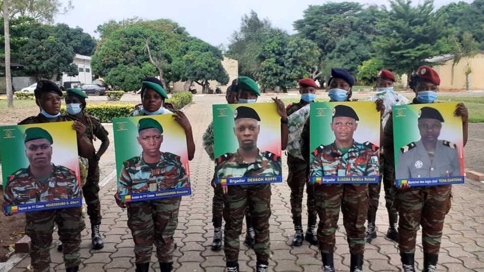 Des soldats béninois portent les portraits des cinq soldats tués dans le parc de la Pendjari, lors d'une cérémonie d'hommage à Cotonou, le 25 mai 2022. © Jean-Luc Aplogan